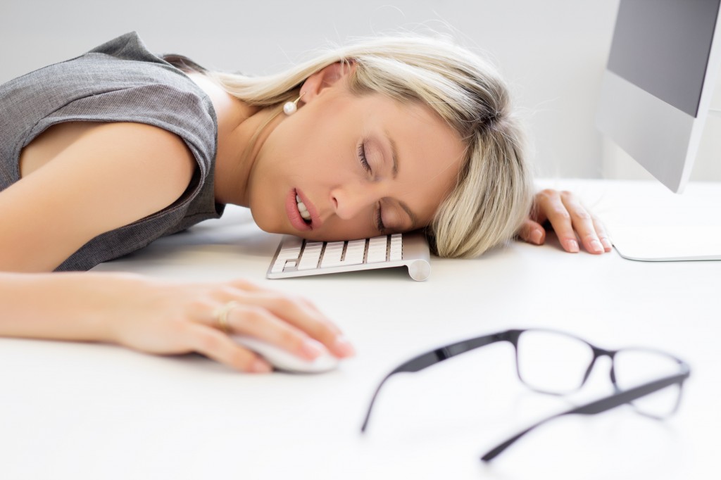 Exhausted woman sleeping at desk in front of computer